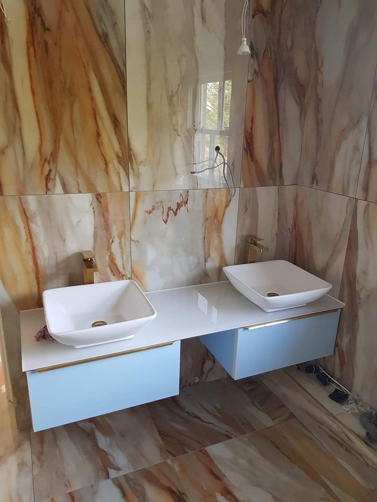 Marble bathroom fit-out with twin vessel sinks and gold fittings