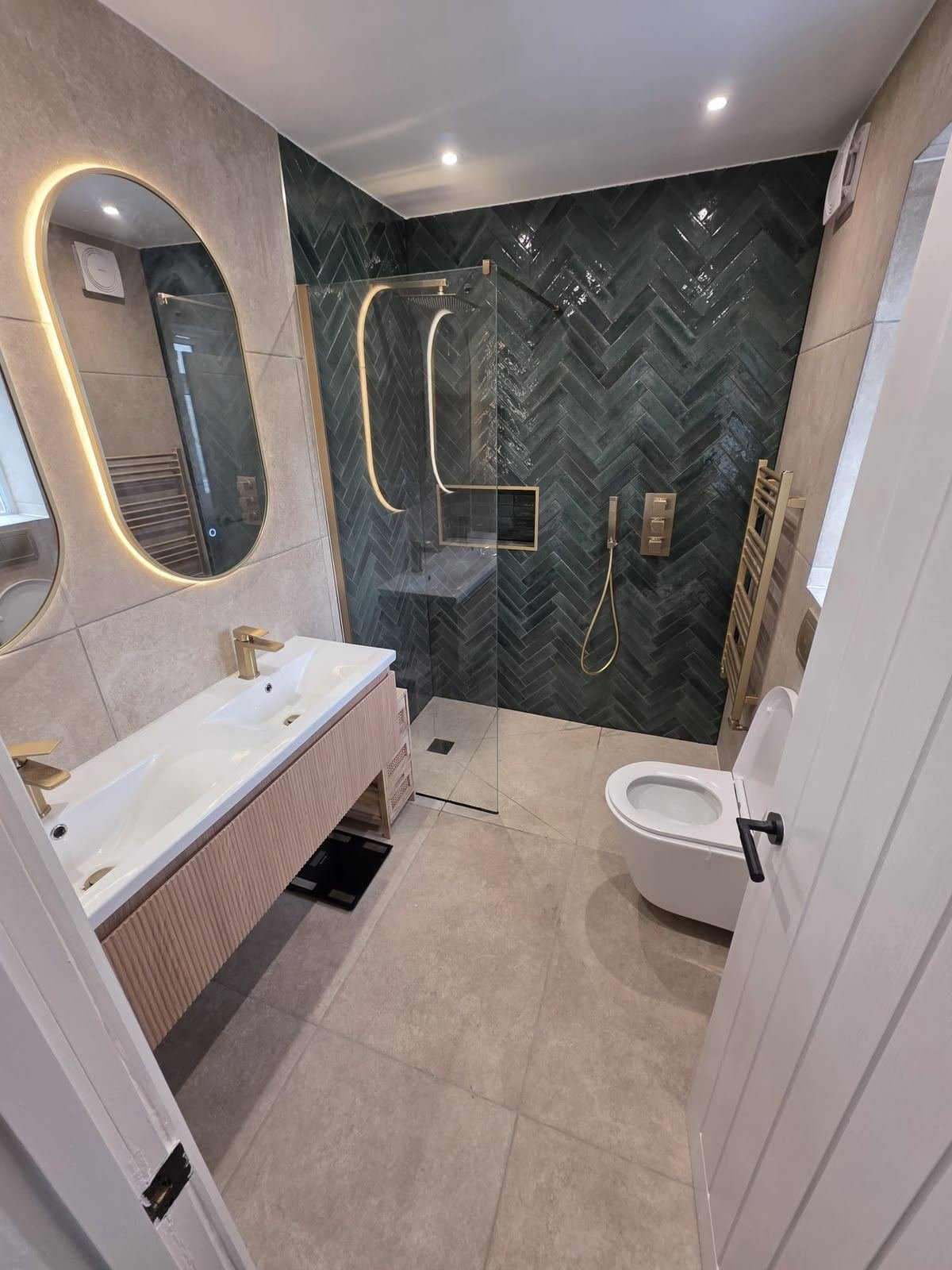 Bathroom with green herringbone tiled shower and gold fittings