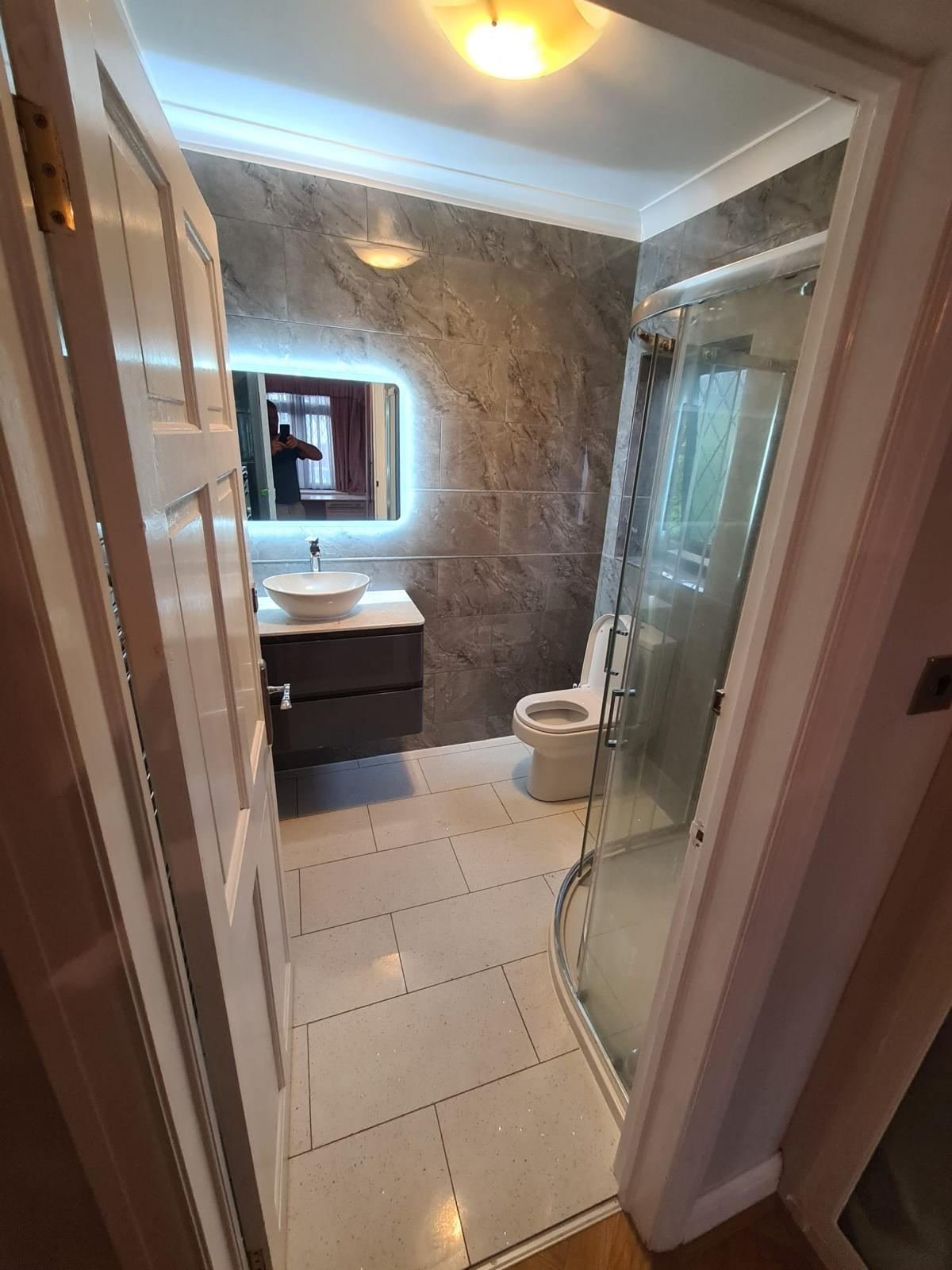 Grey marble bathroom with vessel sink and curved shower enclosure