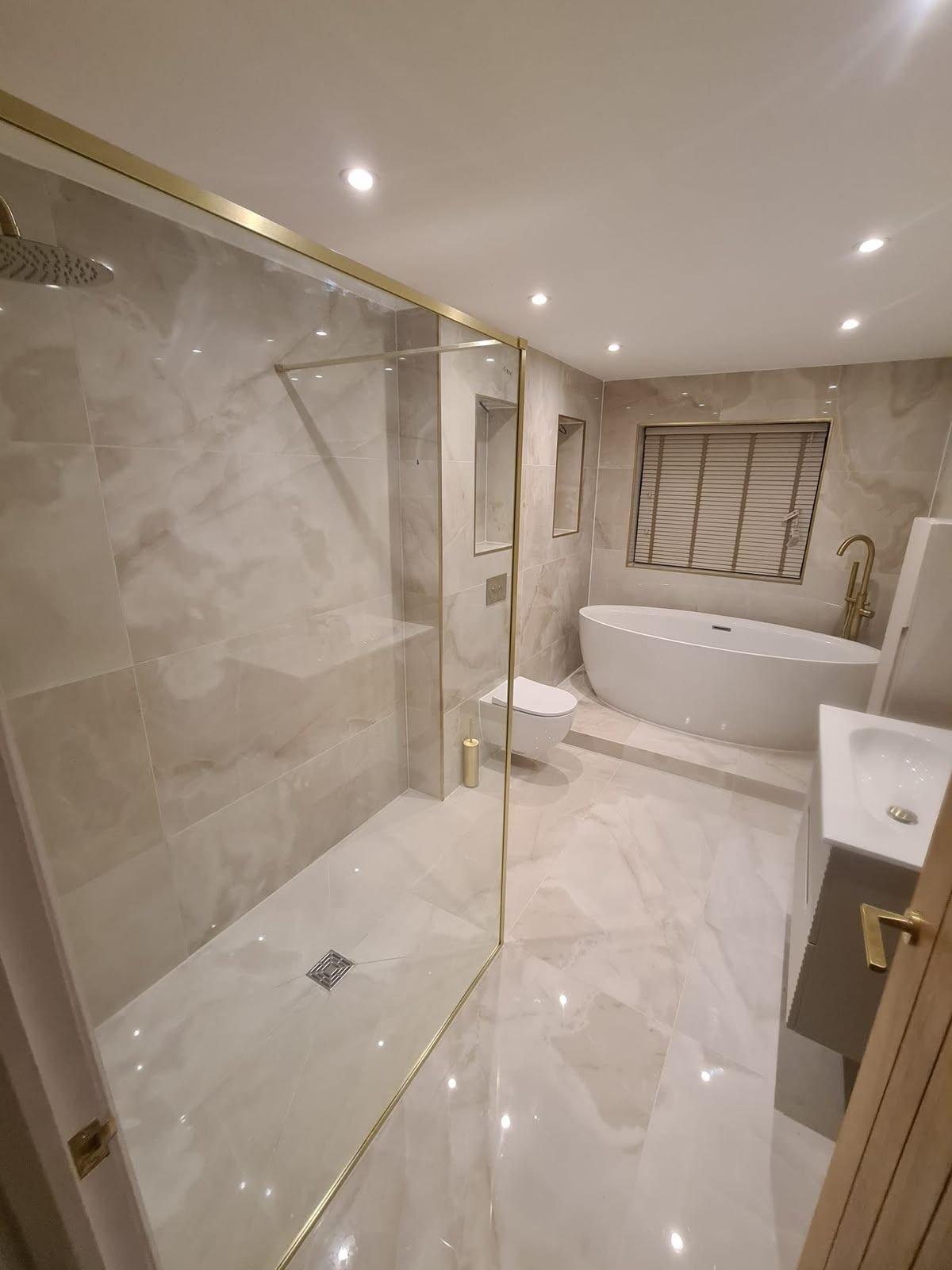 Marble wet room with gold shower screen and freestanding bath