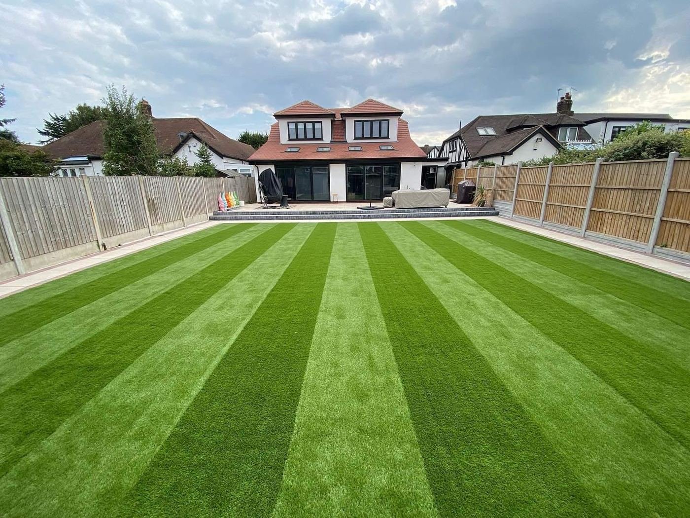 Large rear garden with striped lawn and patio
