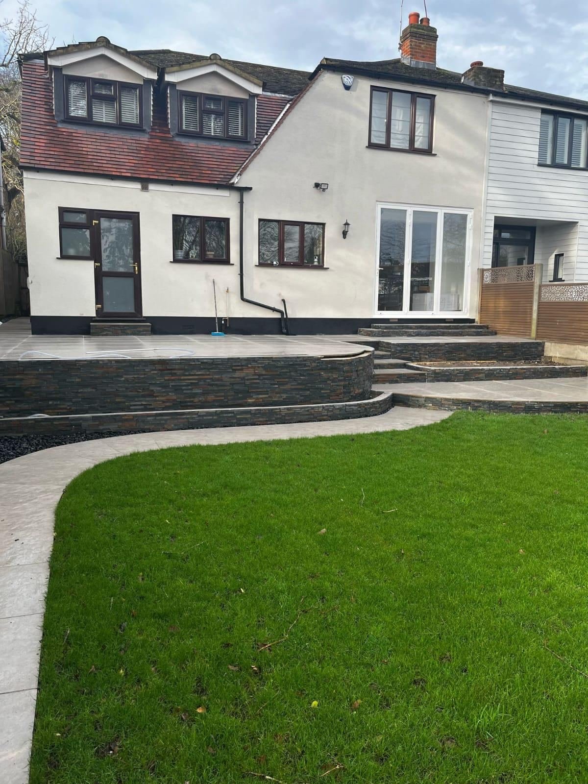 Raised patio with stone-clad retaining walls and curved paving